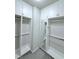Walk-in closet includes custom white cabinets, shelves, hanging rods, mirror and grey carpet at 992 Harvest Park Ln, Suwanee, GA 30024