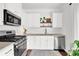 Modern kitchen featuring stainless steel appliances, white cabinetry, and a cozy aesthetic at 833 Society Ct, Woodstock, GA 30188