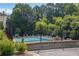 Community pool area surrounded by lounge chairs, umbrellas and green landscaping at 833 Society Ct, Woodstock, GA 30188