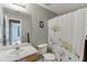 A gray bathroom with a toilet, white shower curtain, and sink with vanity at 992 Harbins Pass Dr, Dacula, GA 30019