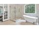 Bright bathroom with a soaking tub, glass shower, and large window overlooking greenery at 5588 Rhododendron Trl, Douglasville, GA 30135