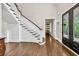 Elegant foyer featuring gleaming hardwood floors, a grand staircase, and natural light streaming through the glass front door at 5588 Rhododendron Trl, Douglasville, GA 30135