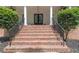 Inviting brick staircase leading to the front entrance, framed by manicured greenery and elegant black handrails at 5588 Rhododendron Trl, Douglasville, GA 30135