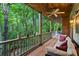 Spacious back porch featuring comfortable seating and a ceiling fan with views of the surrounding trees at 2910 Leeds Garden Ln, Alpharetta, GA 30022