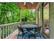 Relaxing back porch with a dining table and chairs, surrounded by lush trees and natural scenery at 2910 Leeds Garden Ln, Alpharetta, GA 30022