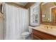 Classic bathroom with a shower featuring a white curtain, a vanity with a gold faucet, and decorative wallpaper at 2910 Leeds Garden Ln, Alpharetta, GA 30022