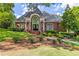 Elegant brick building with a prominent arched entryway, manicured landscaping, and lush green lawn at 2910 Leeds Garden Ln, Alpharetta, GA 30022