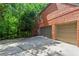Brick home featuring an attached garage with two bays and a spacious driveway, surrounded by lush trees at 2910 Leeds Garden Ln, Alpharetta, GA 30022