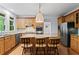 Well-lit kitchen boasting stainless steel appliances, granite countertops, wood cabinets, and a kitchen island with barstool seating at 2910 Leeds Garden Ln, Alpharetta, GA 30022