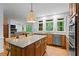 Open kitchen with granite countertops, wood cabinets, a large island with barstool seating, and windows overlooking the backyard at 2910 Leeds Garden Ln, Alpharetta, GA 30022