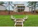 Backyard with green grass, tiered yard, screened porch, and fire pit with chairs for entertainment at 4840 Chase Ln, Cumming, GA 30040