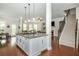 Kitchen island with granite countertops, pendant lights, and a view of the staircase and living space at 4840 Chase Ln, Cumming, GA 30040
