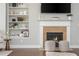 Living room fireplace with beige tiled hearth and mantle with wall decor, built-in shelves with decorative objects at 4840 Chase Ln, Cumming, GA 30040