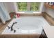 Close-up on soaking tub in main bathroom featuring tile surround and a large window at 4840 Chase Ln, Cumming, GA 30040