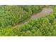Aerial view of a serene lake surrounded by lush greenery and a home nestled within a wooded setting at 15 Bailey St, Whitesburg, GA 30185