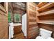 Wood paneled bathroom with rustic shelves and a white toilet at 15 Bailey St, Whitesburg, GA 30185