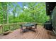Wooden deck with outdoor table and grill, surrounded by lush greenery at 15 Bailey St, Whitesburg, GA 30185