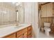 Well-lit bathroom featuring vanity with framed mirror, adjacent toilet and tiled shower/tub at 11880 Wexford Club Dr, Roswell, GA 30075