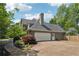 Home's exterior featuring a garage, circular driveway, and manicured landscaping at 11880 Wexford Club Dr, Roswell, GA 30075