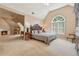 Spacious main bedroom with fireplace and luxurious furnishings, including a sitting area and arched window at 11880 Wexford Club Dr, Roswell, GA 30075