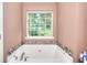 Close up of soaking tub and tile surround with large window offering natural light in bathroom at 2314 Robin Dr, Loganville, GA 30052