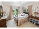 A bedroom with a four-poster bed, pink accents, and multiple windows overlooking lush greenery at 111 Terrace Ne Dr, Atlanta, GA 30305