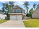 A two-story brick home featuring a two-car garage, surrounded by a well-manicured lawn and wooden fence at 154 Stephens Mill Dr, Dallas, GA 30157
