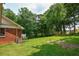 View of the home's backyard featuring a wooden deck, brick exterior, and lush green lawn at 3223 Heritage Way, Buford, GA 30519