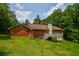 View of the home's backyard featuring a wooden deck, brick exterior, and lush green lawn at 3223 Heritage Way, Buford, GA 30519