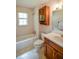 This bathroom features a shower and bathtub combo, wooden cabinets, and natural light at 3223 Heritage Way, Buford, GA 30519