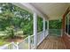 Inviting front porch with wooden floor, white railing, and peaceful greenery at 3223 Heritage Way, Buford, GA 30519