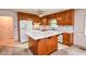 Functional kitchen boasts wood cabinets, center island, and white appliances at 3223 Heritage Way, Buford, GA 30519