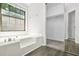 Bright bathroom with large tub, window and walk in closet featuring laminate flooring at 998 Pointer Rdg, Tucker, GA 30084