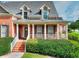 Close-up of the home's inviting front porch with brick stairs, white columns, and lush green landscaping at 3145 Sweet Basil Ln, Loganville, GA 30052
