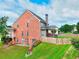 Two story home featuring brick and neutral siding, a wood fence, a back patio, and a well-maintained lawn at 3145 Sweet Basil Ln, Loganville, GA 30052