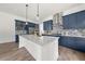 Bright kitchen featuring navy cabinetry, stainless steel appliances, mosaic backsplash, and an island with a marble countertop at 382 Tillman Pass, Woodstock, GA 30188