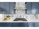 Kitchen with navy cabinets, stainless steel range hood, gas cooktop, and detailed mosaic tile backsplash at 382 Tillman Pass, Woodstock, GA 30188