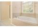 Bright bathroom with large tub, tiled surround, and natural light from the window at 5821 Saint Miles Drive Dr, Buford, GA 30518