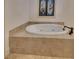 Corner soaking tub with tile surround and stylish fixtures under a stained glass window at 4853 Stonehall Pl, Atlanta, GA 30339