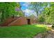 Lush backyard featuring an expansive lawn, wood fence, brick structure, and stairs at 1026 Reeder N Cir, Atlanta, GA 30306
