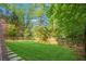 Expansive backyard with well-kept lawn, a wood fence, and stone walkway with lush foliage at 1026 Reeder N Cir, Atlanta, GA 30306