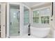 Bright bathroom featuring a modern soaking tub with a glass shower and views of the outdoors at 980 Fenimore Cir, Atlanta, GA 30350