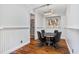 Well-lit dining room featuring wainscoting, a modern chandelier, and a glimpse into the wine cellar at 980 Fenimore Cir, Atlanta, GA 30350