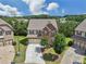Aerial view of a brick home with a well-kept lawn, driveway, and tree-lined neighborhood at 4480 Egret Ave, Cumming, GA 30041