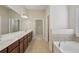 Main bathroom with dual sink vanity, soaking tub, and walk-in closet entrance at 4480 Egret Ave, Cumming, GA 30041