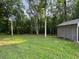 Large, grassy backyard with mature trees, partially fenced with a gray house visible at 1713 Cagle Ct, Lawrenceville, GA 30045