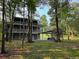 View of a home's back exterior featuring a multi-level deck and covered parking, surrounded by trees and lawn at 1713 Cagle Ct, Lawrenceville, GA 30045