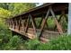 Wooden covered bridge with visible support beams, surrounded by lush green trees and foliage at 2010 Riverside Rd, Roswell, GA 30076