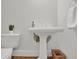 Powder room view with a white pedestal sink, toilet, basket and neutral wall color at 2010 Riverside Rd, Roswell, GA 30076