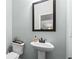 Well-lit half-bath with a stylish pedestal sink, framed mirror, and neutral wall color at 572 Boulder View Pkwy, Dallas, GA 30157